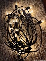 String lights plugged in, bulbs illuminated, coiled on carpet