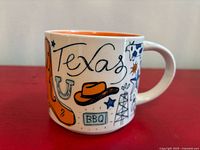 Front view of mug showing Texas script, cowboy boot, hat, horseshoe, oil derrick graphics