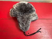 Front profile of faux fur trapper hat with earflaps folded down