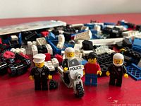 Four minifigures, police motorcycle, loose bricks pile in background