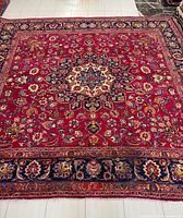 Full view of red Mashhad rug showing central medallion and overall design
