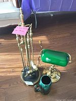 Overall lot showing fireplace tools, banker’s lamp and green mug