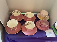 Six pink Aynsley teacup and saucer sets arranged together