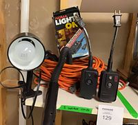 Overall lot showing clamp light, inspection light, two switch adapters, coiled orange cords, Noma timer box