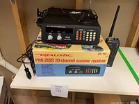Realistic PRO-2020 scanner on its original box, handheld scanner with antenna beside, cords visible
