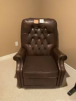 Front view of dark brown leather manual recliner showing tufted back and rolled arms