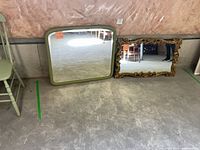 Both mirrors leaning against wall showing frames and glass