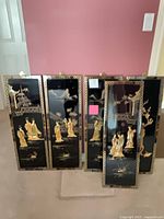 Front view of five black lacquer panels with carved figures and gilt accents