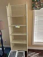 Full view of off-white wicker étagère with six shelves and wire risers on floor