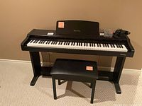 Front view of Technics digital piano on stand with bench, headphones and accessories visible