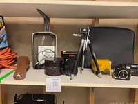 Full shelf view showing camera, tripod, film box, cases and accessories