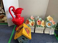 All items together: red ceramic pitcher, three floral planters, painted birdhouse