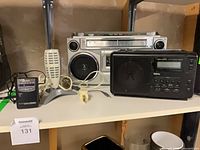 Shelf view showing silver boombox, black Realistic radio, microphone, AC adapter and plug adapter
