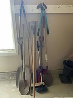 Group view of all long-handled tools leaning against wall