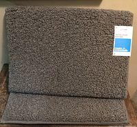 Two grey memory foam bath mats folded with retail tag attached