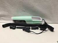 Handheld mint-green vacuum cleaner with hose, attachments and power cord