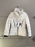 Front view of beige LPGA puffer coat on hanger showing overall design, pockets and tag