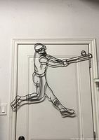Full view of wrought iron baseball batter wall art hanging on door