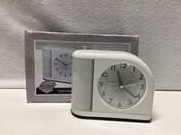 Front view of white analog alarm clock and original box
