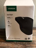 Front of sealed retail package showing UGREEN branding, mouse image, 4000 DPI, dual-mode wireless icons