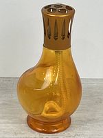 Full view of amber glass Lampe Berger with crown and wick
