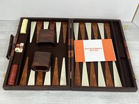 Open case showing board, checkers, dice, cups, rulebook