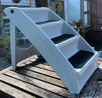 Side view of plastic folding pet stairs fully extended on deck