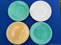 Top view of four plates in ivory, orange, two greens