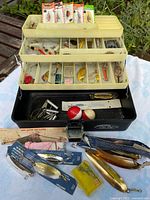 Open tackle box displaying trays with lures, sinkers, bobbers, packaged lures