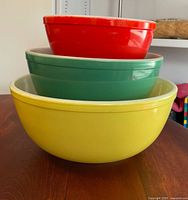 Nested yellow, green, red Pyrex bowls side view