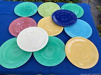 Top view of all eleven multi-coloured plates laid out