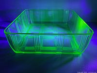 Dish glowing under UV light showing uranium glass fluorescence