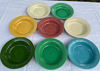 Eight Fiesta bowls in assorted colors displayed on white cloth