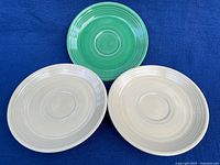 Front view of three saucers showing colors and concentric ring design