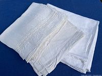 Folded stack of linen towels showing damask and lace details next to folded tablecloth