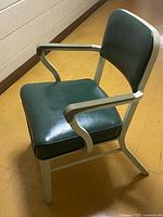 Three-quarter front view of chair showing green vinyl seat/back and white steel frame