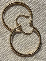 Both gold hoop earrings on fabric background