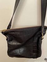 Front view of black croc-embossed leather shoulder bag hanging