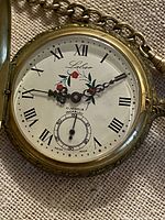 Pocket watch dial showing Labar branding, floral motif, Roman numerals, sub-seconds