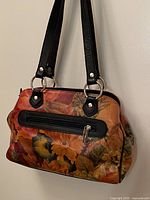 Front view showing floral print, black trim, top zipper and exterior zip pocket