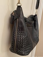 Side angle highlighting woven leather panel and gold-tone clasp