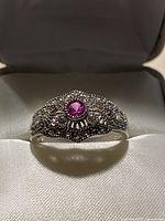 Top view of sterling silver filigree ring showing centre lab ruby/sapphire and surrounding cubic zirconia