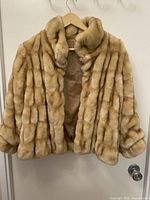 Front view of blonde/champagne real fur jacket on hanger
