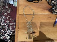 Full view of gold-tone Art Deco style necklace on wood surface