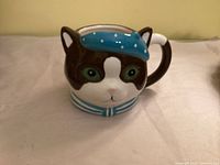 Front view of ceramic cat face mug showing painted details