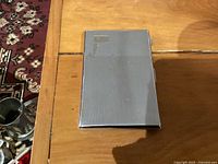 Closed rectangular chrome cigarette case on wooden surface