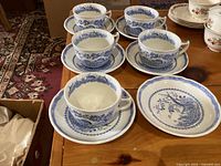 Set of 5 blue-and-white cups with 6 saucers arranged on table