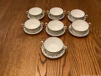 Seven cream soup bowls with saucers arranged on table