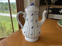 Front view of white porcelain coffee pot with blue floral pattern and lid