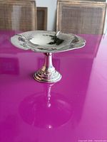 Sterling silver pedestal dish front view on purple surface
